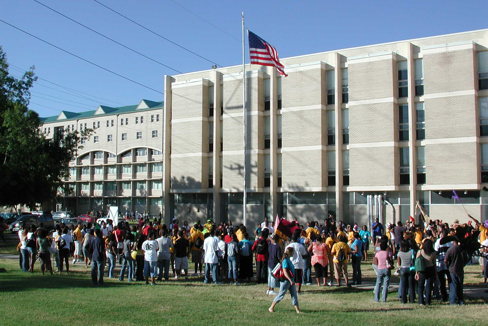 Students standing on the grounds of a high school or college campus. 